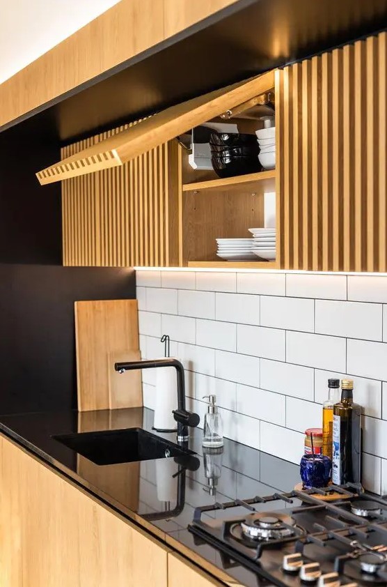 a bold and contrasting kitchen with elegant black finishes contrasted with light stained ribbed cabinets