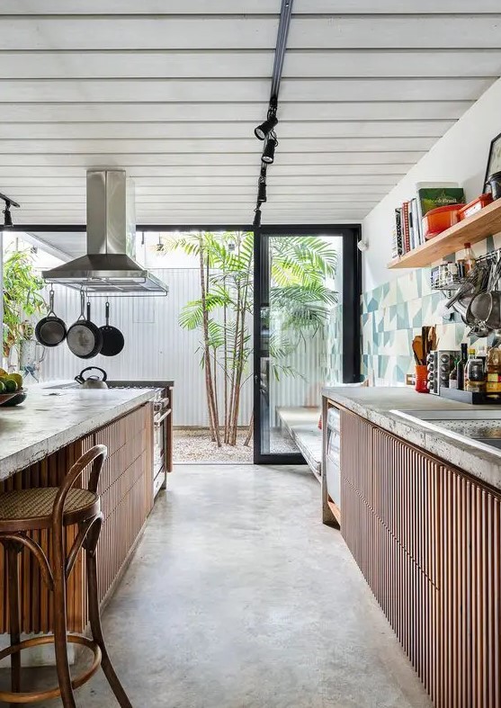 a cool indoor-outdoor kitchen with ribbed cabinets, concrete countertops and a large matching kitchen island with dining area