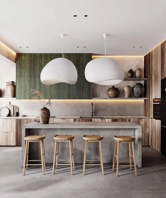 a beautiful kitchen with stained base cabinets and green fluted upper cabinets, a concrete kitchen island, wooden stools and statement vases