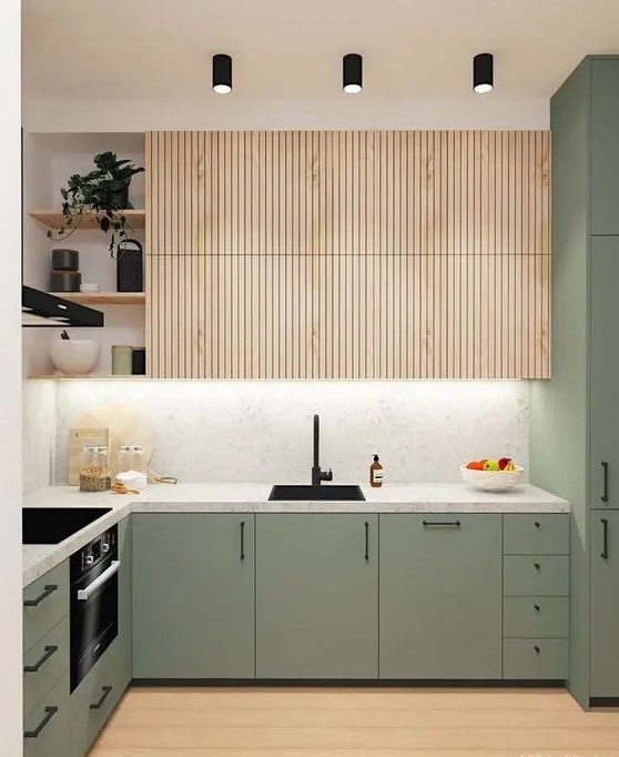 a cool, modern kitchen with simple green cabinets and fluted, stained upper cabinets, a white stone countertop and backsplash, and black fixtures