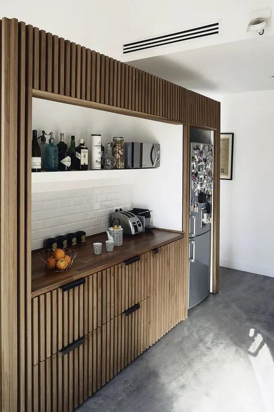 A small fitted kitchen with ribbed cabinetry, a white subway tile backsplash and open shelving is cool