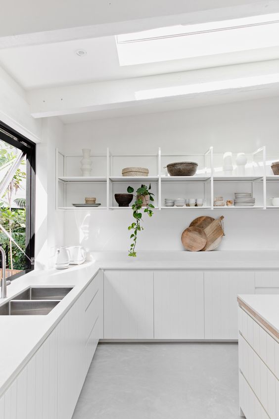 a chic, modern kitchen in white with elegant cabinets, open shelving instead of upper cabinets and skylights