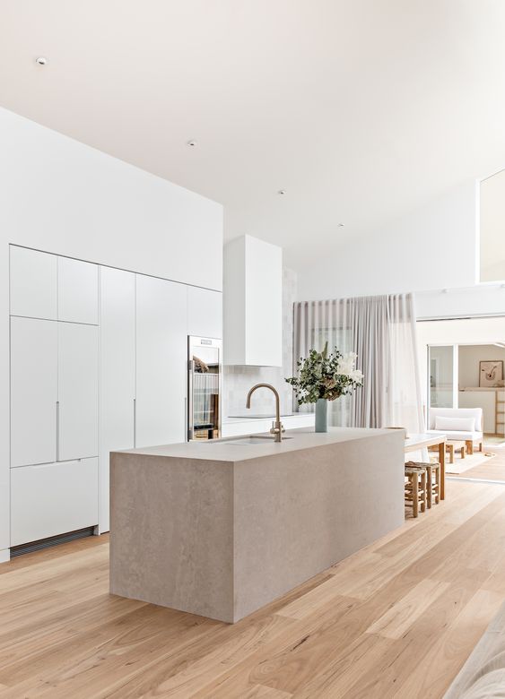 A minimalist white kitchen with sleek cabinets and a stone countertop island looks amazing