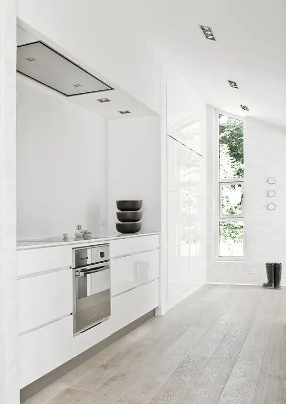 A minimalist, white room with sleek cabinets and a vertical window that lets in lots of light feels clean and fresh