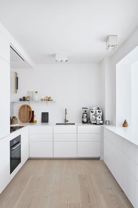 an ultra-minimalist white kitchen with sleek cabinets, open shelving, built-in appliances and a large window