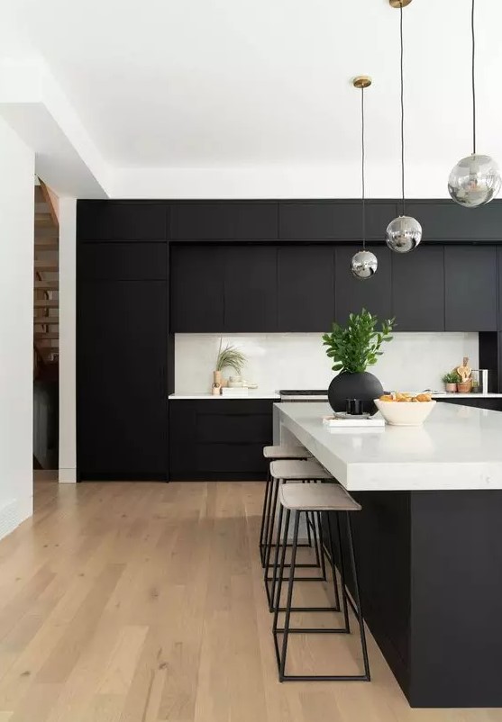a modern black and white kitchen with matte cabinets, white countertops as well as a backsplash and bubble lamps