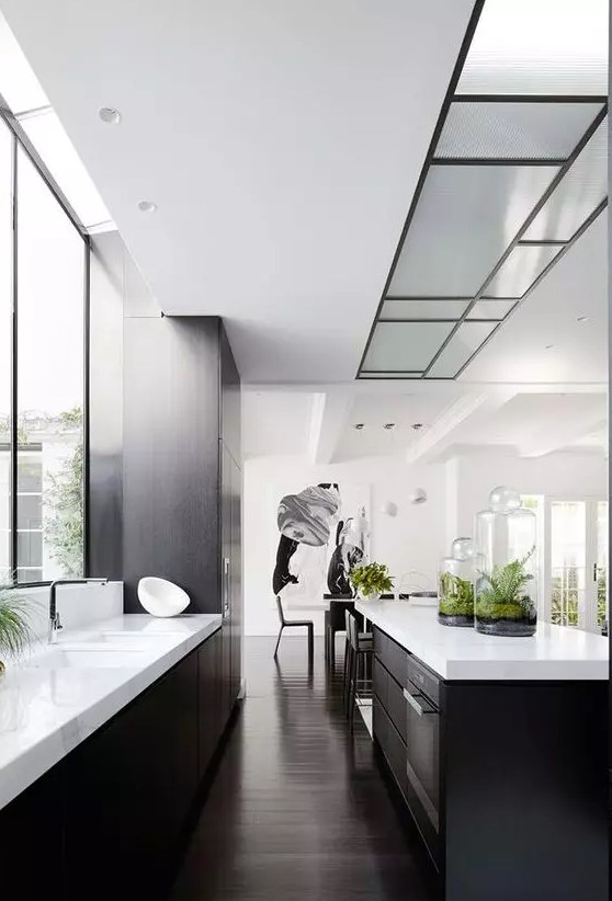 a modern black and white kitchen with white countertops, a window backsplash and built-in lighting