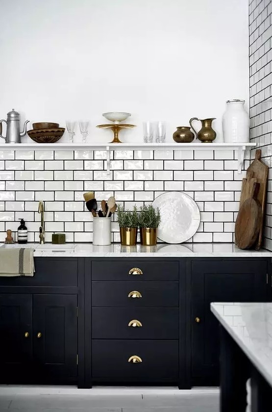 A beautiful mid-century modern kitchen with black cabinets, white stone countertops, a white subway tile backsplash, and black grout