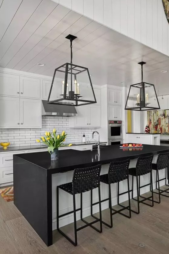 A mid-century modern kitchen with white shaker cabinets, a white thin tile backsplash, a black and white kitchen island, and black woven stools