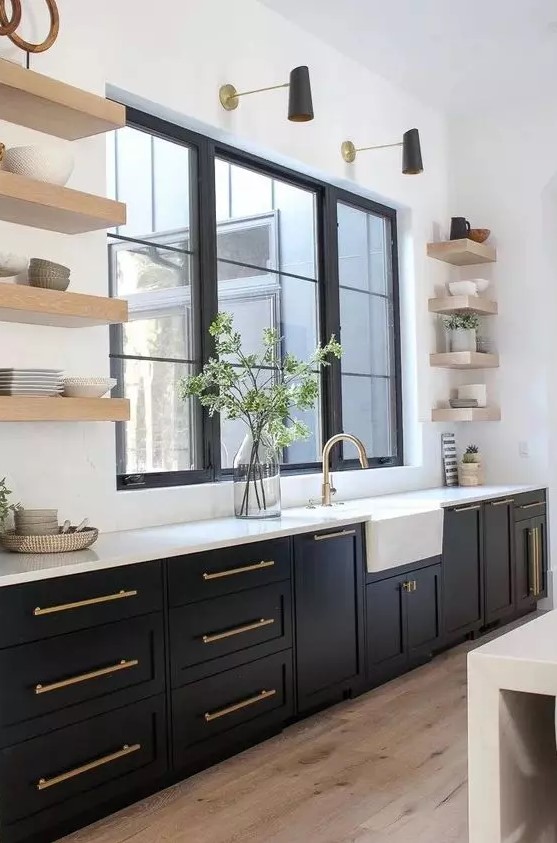 a modern farmhouse kitchen with black shaker cabinets, white countertops and statement floating shelves, and black and gold sconces