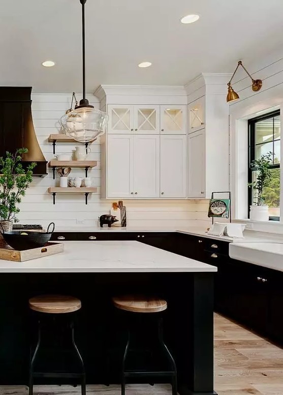 A sophisticated farmhouse kitchen with white upper cabinets and black lower cabinets, white stone worktops and a white floorboard tile backsplash