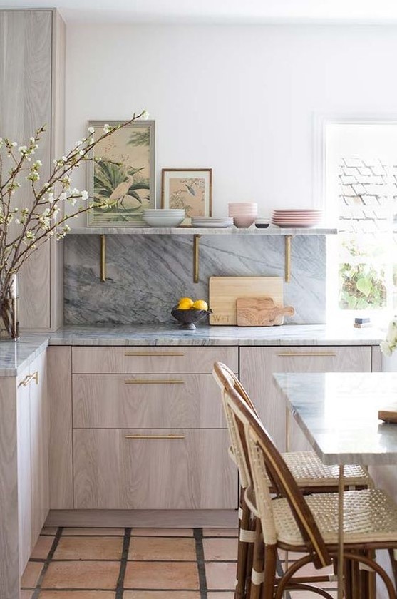 A chic, modern kitchen with neutral cabinets, a gray backsplash and countertops, and touches of gold for added chic