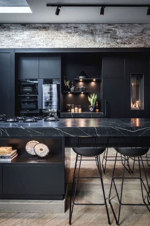 a modern black kitchen with a large kitchen island with marble countertop, built-in lamps and metal stools