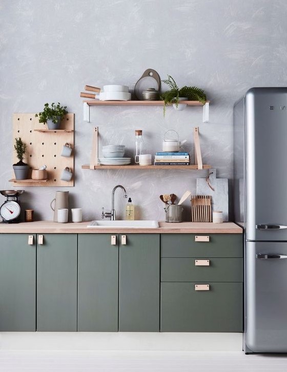 A modern dark green kitchen with a wallpaper wall, plywood shelves and a gray refrigerator is chic and stylish