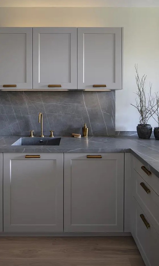 A modern gray kitchen with a backsplash and worktops made of gray marble and brass fittings is a very chic and bold solution