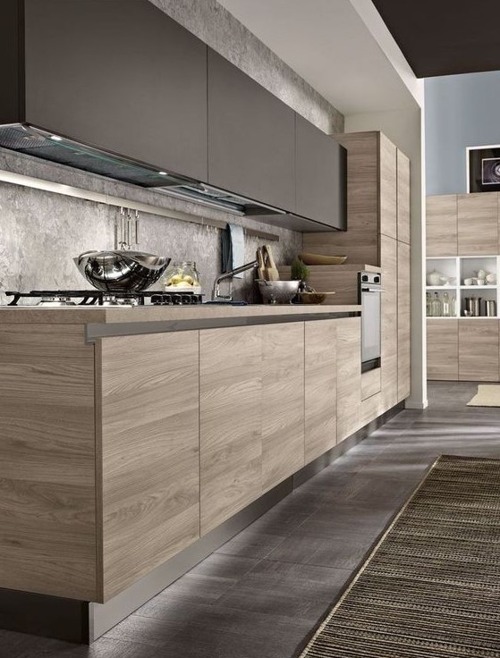 A modern kitchen with matt taupe cabinets, stained base units, gray stone backsplash and worktops and metal hardware