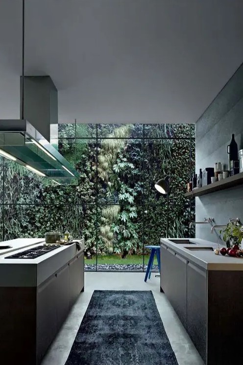 a modern kitchen with sleek dark cabinets, white stone countertops, open shelving, a kitchen island and a glass wall that showcases the greenery of a private garden