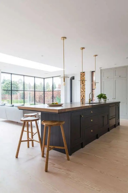 a modern light gray kitchen with a contrasting navy island and a small dining area with some stained wooden stools