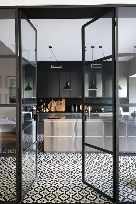 a modern, atmospheric kitchen with polished metal cabinets, a black backsplash and countertops, and black pendant lamps