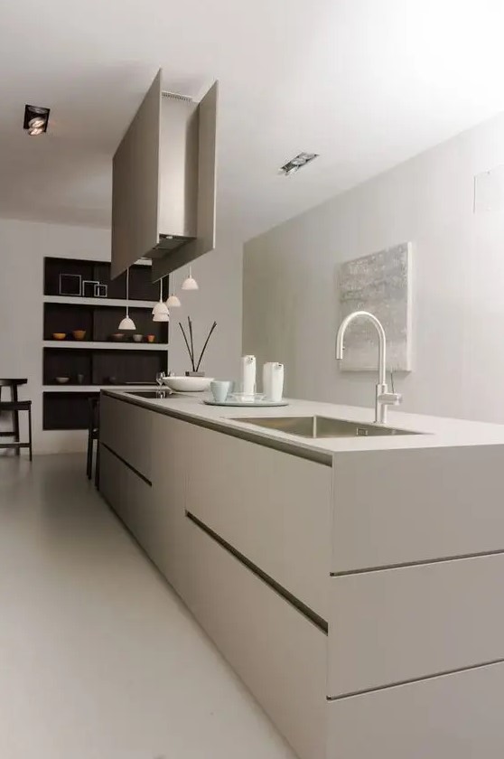 A modern to minimalist kitchen in greige with an elegant kitchen island, extractor hood, pendant lamps and niche shelves is amazing