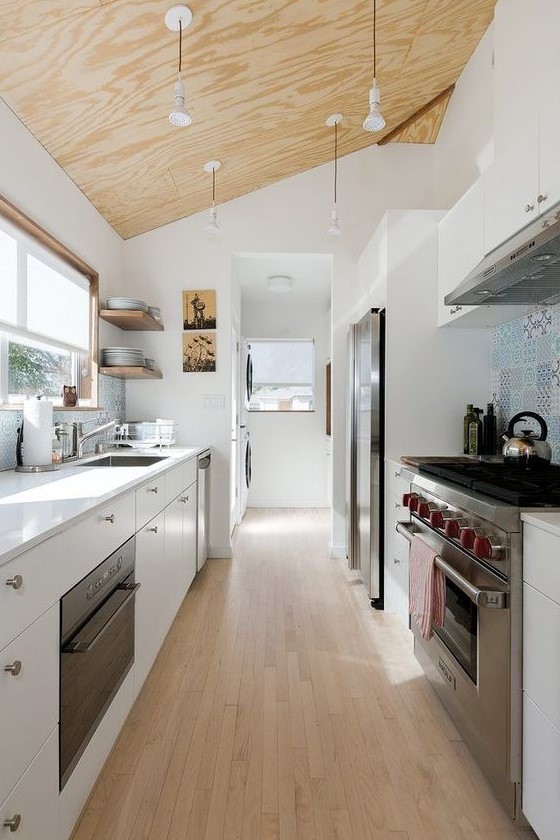 A modern white loft kitchen with a blue tile backsplash, white countertops and modern appliances is chic