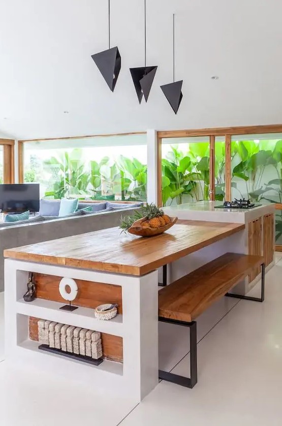 A pretty modern kitchen in white with stained wood and a glazed wall that opens onto a tropical garden
