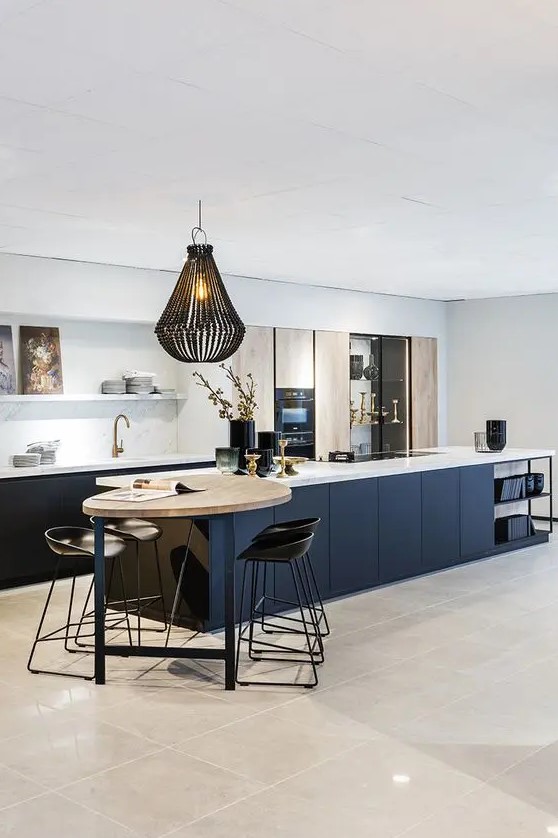 a sophisticated modern kitchen with navy base cabinets and island, light stained doors, open shelving and a small dining area