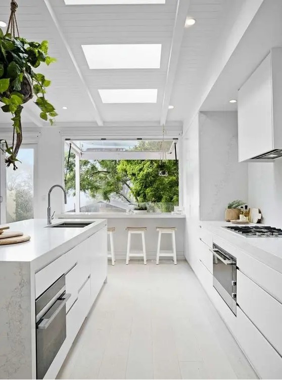 a serene white modern kitchen with sleek cabinets, a large island, white stone countertops and a backsplash