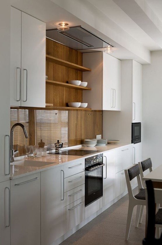 A stylish modern white kitchen with a wooden backsplash covered with transparent glass to make it more durable