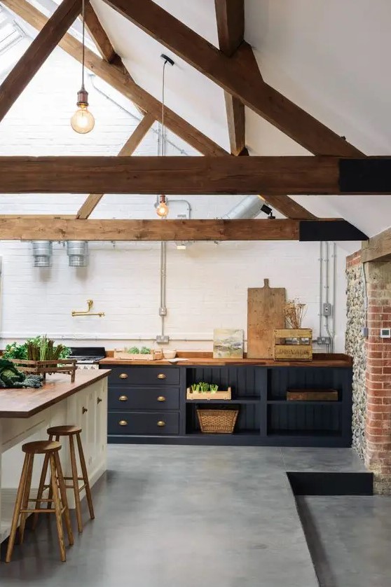 a modern barn kitchen with exposed beams, midnight blue cabinets with butcher block countertops, a white kitchen island and wooden stools