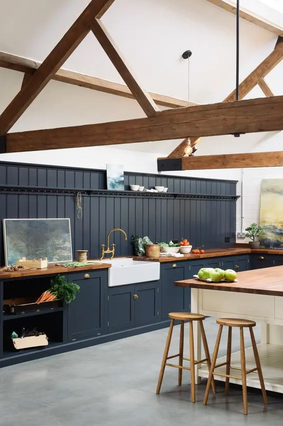 a modern barn kitchen with exposed beams, graphite gray shaker-style cabinets, butcher block countertops and a white kitchen island
