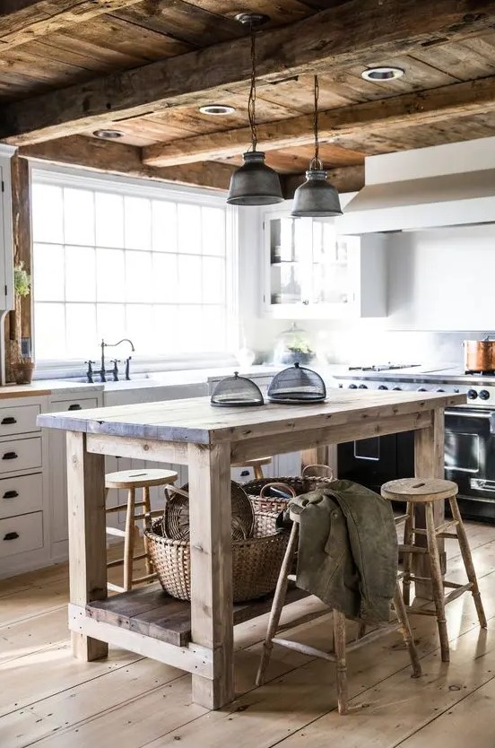 a rustic barn kitchen with white planked cabinets, a kitchen island and reclaimed wood stools, a weathered and distressed wood ceiling with beams