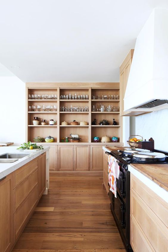A light stained wooden kitchen with wooden worktops, built-in wooden cabinets and a white extractor hood looks very inviting