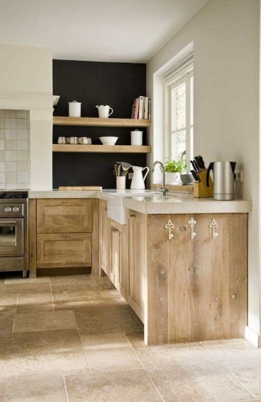 a beautiful kitchen with stained Shaker-style cabinets, a thick stone countertop, a black wall with built-in shelves, and a tile floor