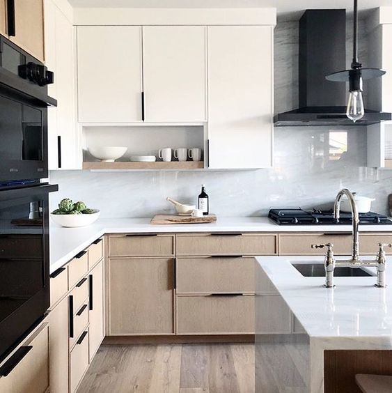 A lovely modern kitchen with white and stained cabinets, comfortable handles, white stone countertops and a white marble backsplash