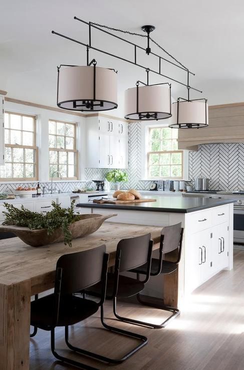 A beautiful modern kitchen in blush, tan and white colors with herringbone tiles, a stained extractor hood, white cabinets and a white kitchen island with plenty of storage space