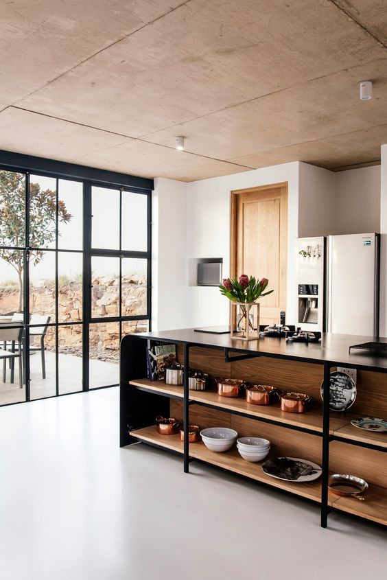 A modern kitchen with a large black metal kitchen island with open shelves is a cool idea to display beautiful tableware