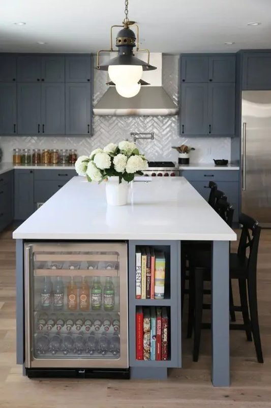 a gray farmhouse kitchen with white gloss herringbone tiles, white countertops, an oversized gray-and-white kitchen island with open counters and a beverage cooler