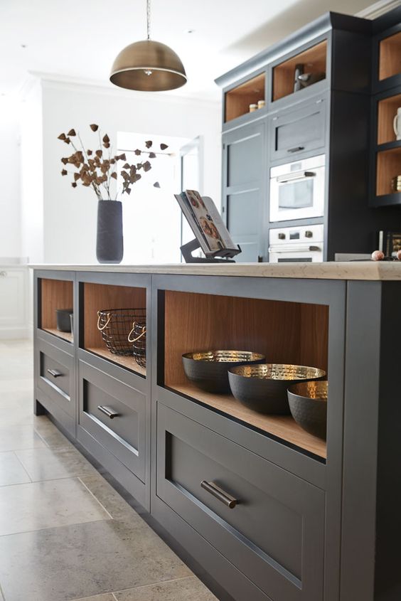 a graphite gray Shaker-style kitchen with stone countertops and an oversized island with drawers and niches for storage