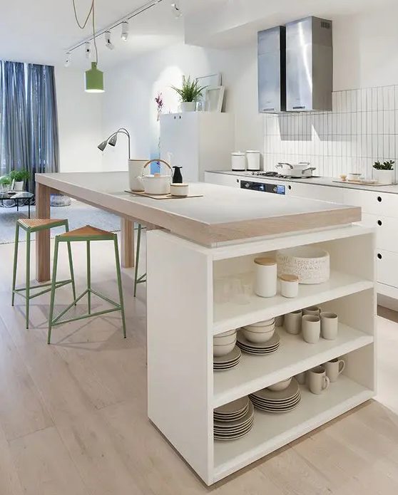 a Nordic kitchen with white cabinets and butcher block countertops, a large kitchen island that serves as a table and an open storage unit for dishes