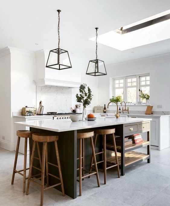 a stylish farmhouse kitchen with white shaker cabinets, white stone countertops, a black kitchen island with drawers and open shelving