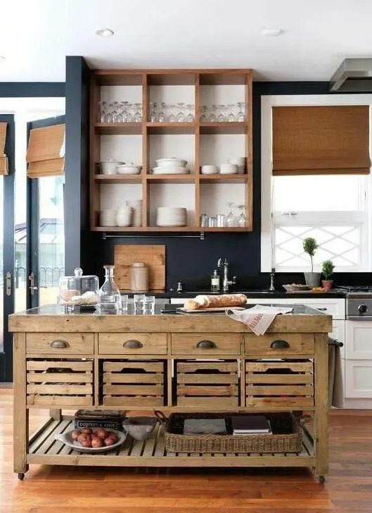 A white and stained farmhouse kitchen with navy blue walls, blinds and a stained wood island with casters, drawers, boxes and baskets is cool
