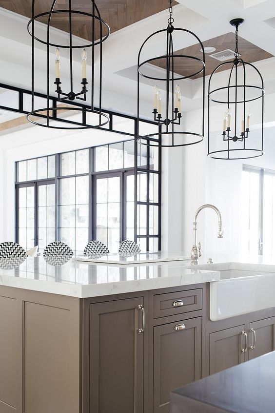 A chic taupe kitchen with shaker cabinets, white stone countertops, and caged pendant lamps is a lovely idea