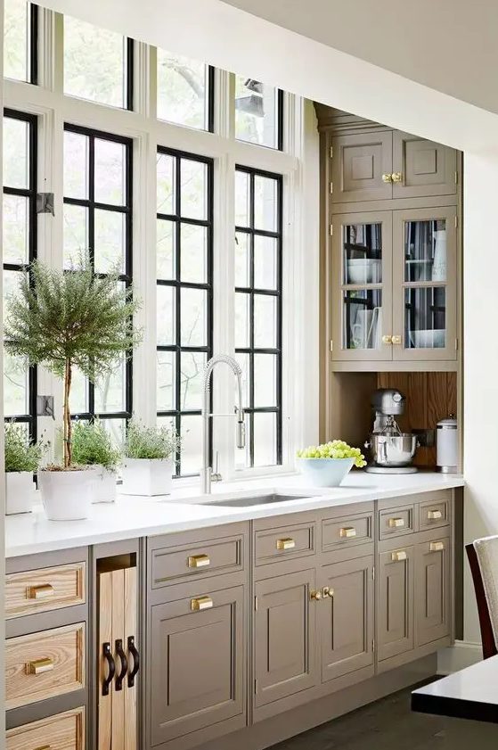 An elegant vintage kitchen with taupe shaker cabinets, white stone countertops, and a window backsplash is a beautiful idea