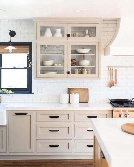A beautiful, light-stained Shaker-style kitchen with a white subway tile backsplash and white quartz countertops and black fixtures