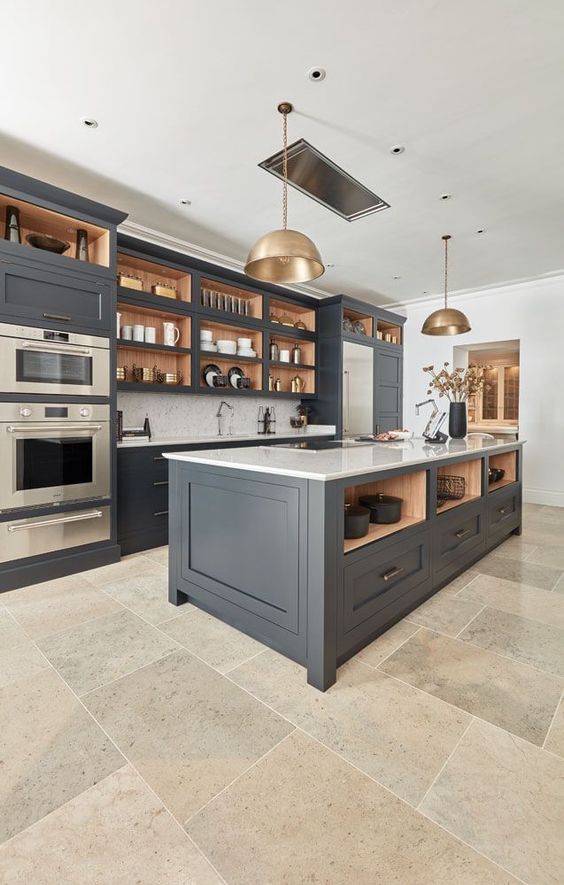 A chic and sophisticated dark gray kitchen with shaker cabinets, white stone countertops, white tiles and brass pendant lamps is cool