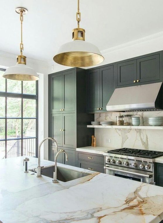 a sophisticated hunter green kitchen with white marble countertops and backsplash, sleek white and gold lamps, and stainless steel appliances