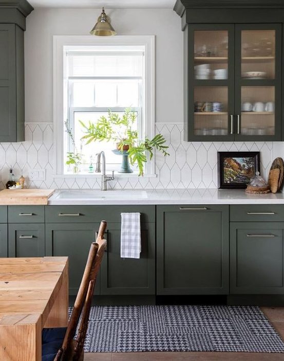 a stylish dark green kitchen with shaker cabinets, white countertops and a white tile backsplash, and retro lamps