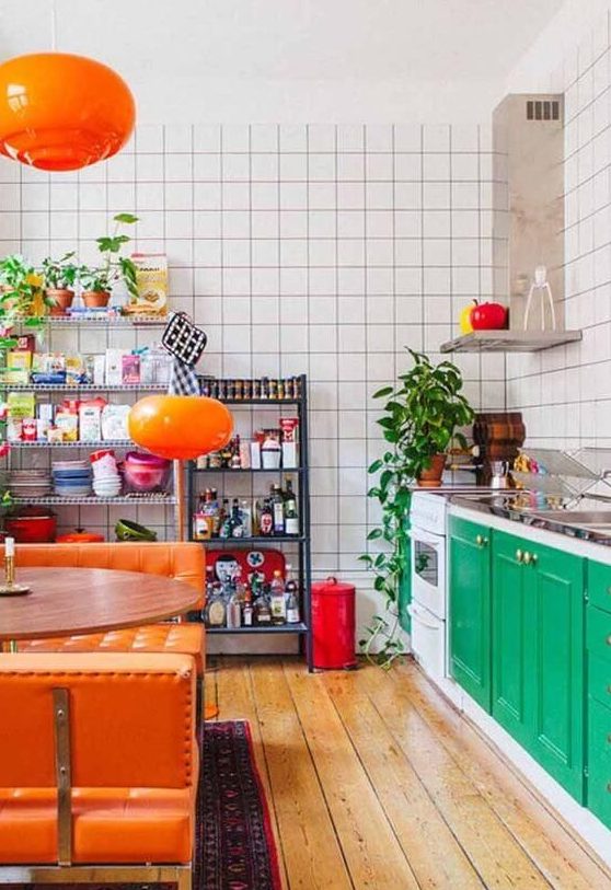 a bold maximalist kitchen with emerald green cabinets, white tile walls, orange upholstered benches and lamps