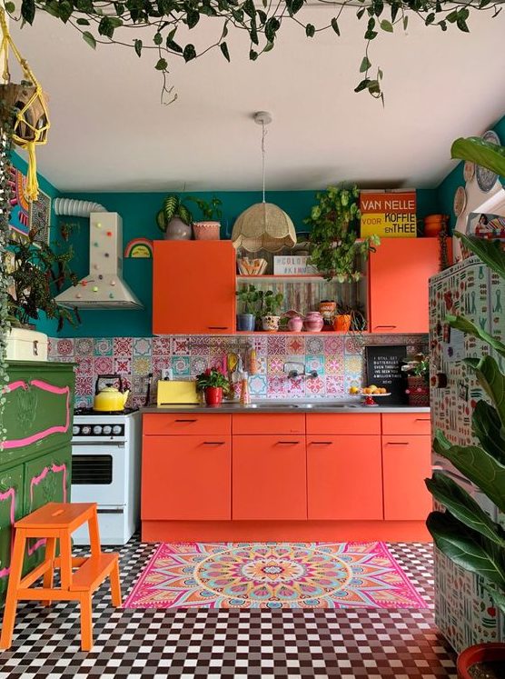 a bright maximalist kitchen with coral furniture, a light floor and carpet, a green wall and a colorful backsplash, and lots of potted plants
